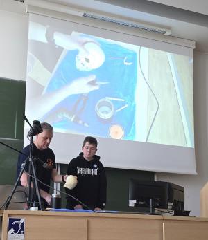 Zdjęcie wykonane podczas symulowanej operacji mocowania implantu do
kranioplastyki przeprowadzonej podczas Ogólnopolskiego Dnia Inżynierii
Materiałowej 2025 w auli kampusu chorzowskiego. Prof. Tomaszowi
Goryczce towarzyszy jego wnuk – Antek Liptak