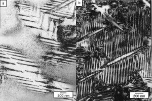 Obrazy struktury stopu NiTi zawierającego soczewkowate cząstki Fazy Ni4Ti3 podczas chłodzenia w elektronowym mikroskopie transmisyjnym. Przemiana martenzytyczna zachodzi najpierw wokół cząstek (a), a następnie, po obniżeniu temperatury, w obszarach pomiędzy cząstkami (b)